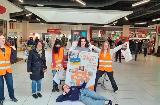 Photo de jeunes participant à la collecte dans un supermarché, la plupart porte un gilet orange